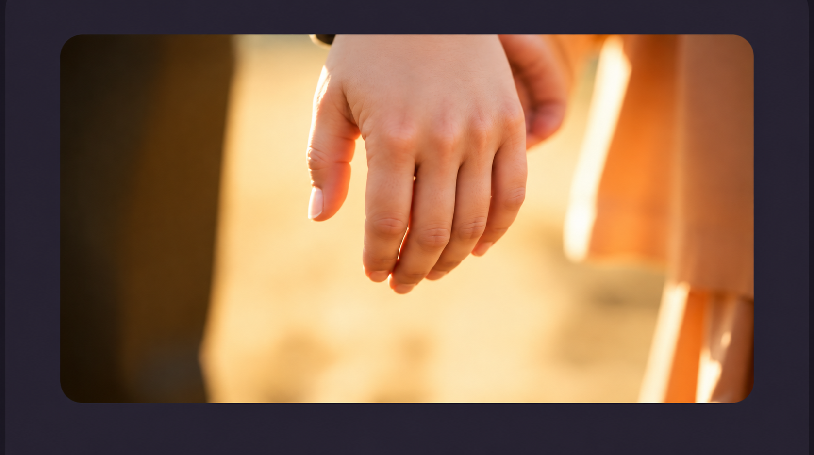An adult hand gently holding a small child's hand in warm golden light