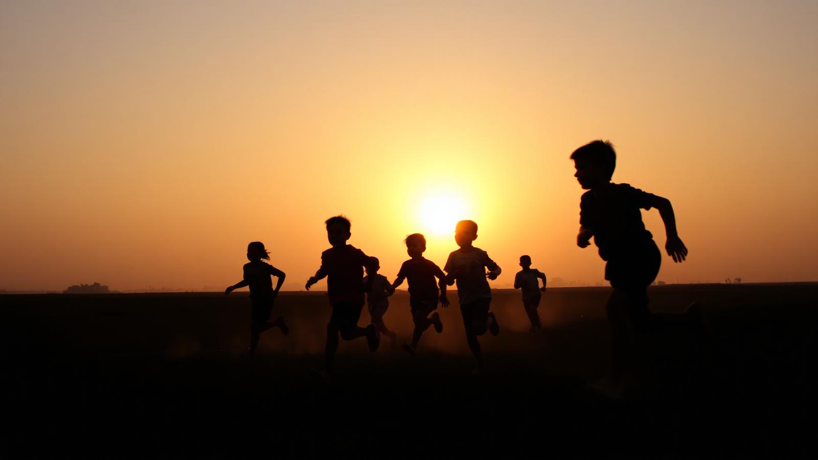 Silhouettes of children running at golden hour